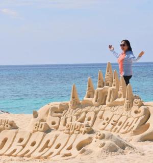 一位女士站在海滩上的沙堡前