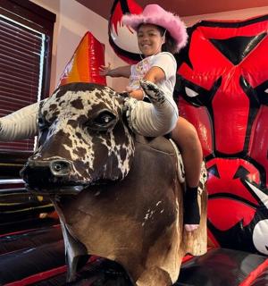 a young woman riding on top of a fake cow