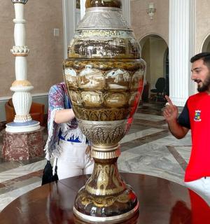 一名男子站在一个大花瓶旁边