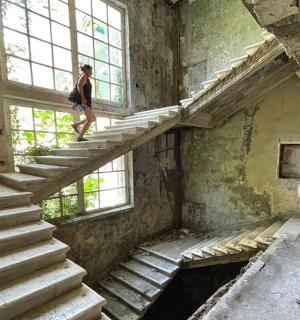 a man standing on the stairs of an abandoned building