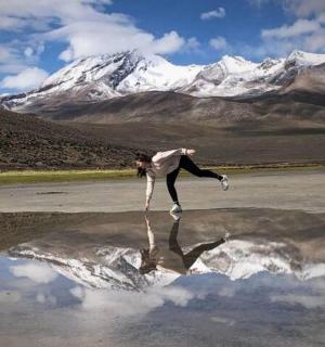 一名女子在山的倒影前跳舞