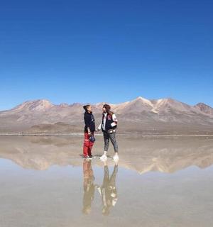 两个人站在水面上,背景是群山