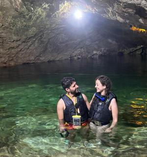 a man and woman standing in the water in a cave
