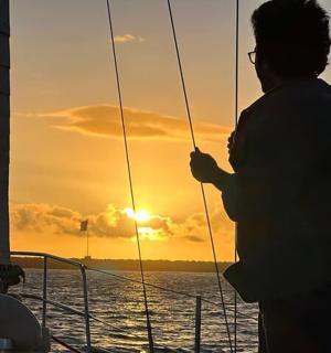 a man standing on a boat at sunset