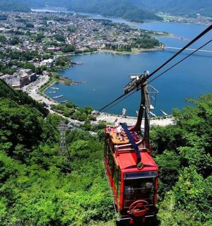 Červená lanovka letící nad kopcem s městem