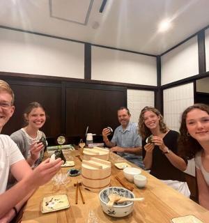 skupina lidí sedících u stolu a jedících sushi