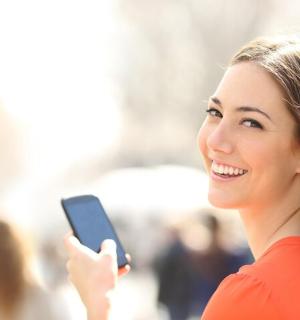 a woman is smiling while holding a cell phone