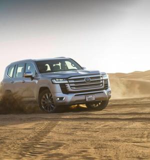 a blue truck driving on a dirt road in the desert