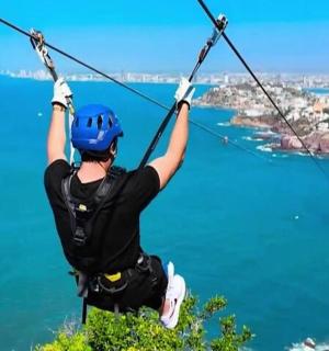 a man on a zip line over the ocean