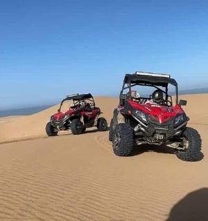 du keturračiai važiuoja per smėlį dykumoje