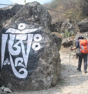 一名背着背包的男子站在岩石旁边