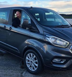 muž sedící v modré dodávce zaparkované vedle jezera