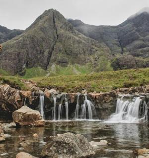 a man standing on a hill next to a waterfall
