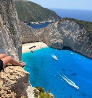 一名女子坐在悬崖上，俯瞰一片水域