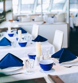 a table with white tables with blue napkins and candles
