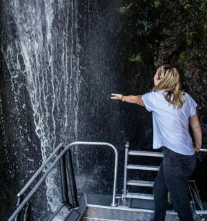一名女子站在瀑布前的台阶上