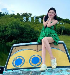 一位身穿绿色连衣裙的女子坐在水中的船上