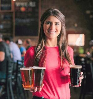 a woman is holding two glasses of beer