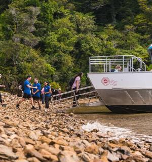 a group of people walking on the shore next to a boat