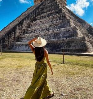 一位身穿连衣裙、头戴帽子的女子站在金字塔前