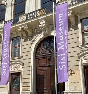 อาคารที่มีป้ายสีม่วงอยู่ด้านหน้า