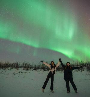 两个人站在北极光下的雪地里