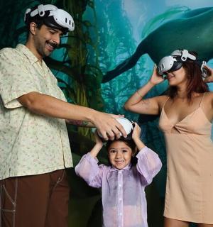 a family standing in front of a aquarium with a dolphin