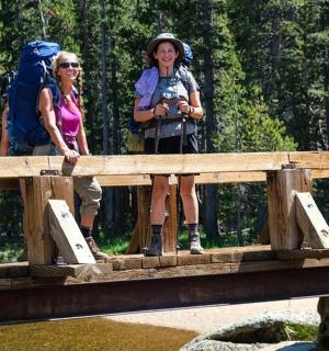zwei Frauen mit Rucksäcken stehen auf einer Brücke