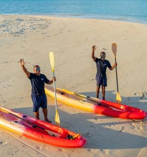 两个男人带着皮划艇站在海滩上