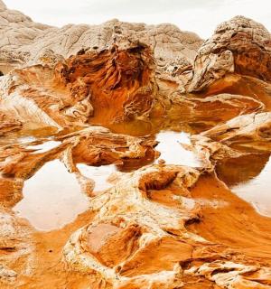 an aerial view of a desert with water and rocks