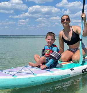 一名妇女和一名儿童坐在水中的桨板上