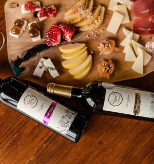 桌上有两瓶葡萄酒、奶酪和水果