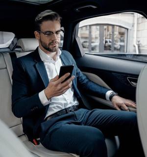 a man sitting in the back seat of a car looking at his cell phone
