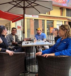 一群人坐在餐厅外的一张桌子旁