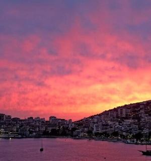 Západ slunce nad vodou s městem v pozadí