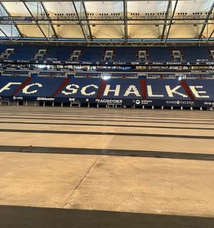 ein leerer Tennisplatz in einem Stadion mit blauen Sitzen