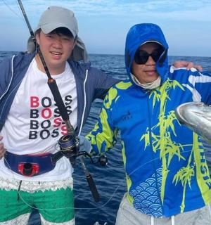 两个男人在船上举着一条鱼