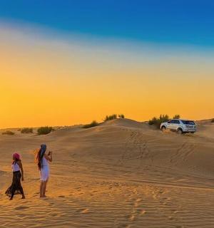 dva lidé kráčející v písku v poušti