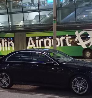 一辆黑色轿车停在一辆公交车前