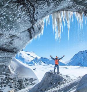 muž stojící před ledovou jeskyní