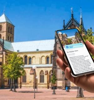 eine Person, die ein Mobiltelefon vor einem Gebäude hält