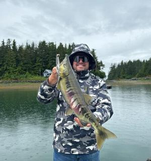 湖边一名男子手里拿着一条鱼