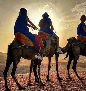 tři lidé jedoucí na hřbetech velbloudů v poušti