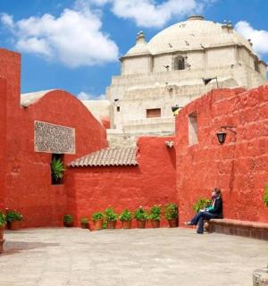 一位女士坐在红墙前的长椅上