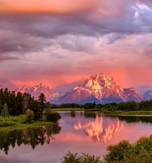a sunset over a river with mountains in the background