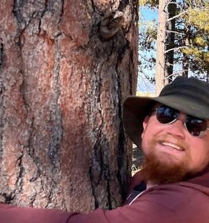 一名戴着帽子的男子站在树旁