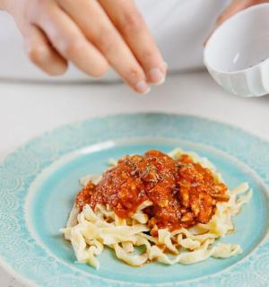 talíř těstovin s masovou omáčkou na stole