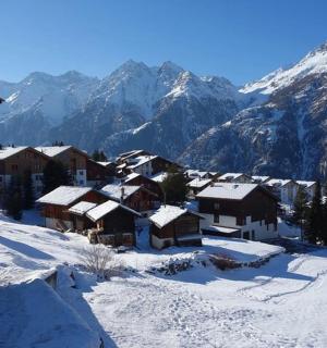 a village covered in snow with mountains in the background