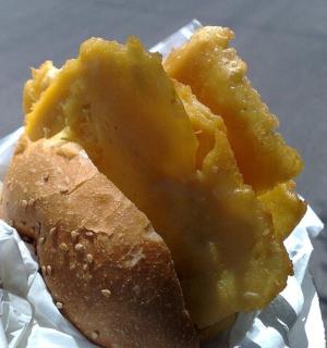 a person holding a piece of food with cheese