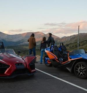 skupina lidí stojící vedle dvou motocyklů na parkovišti